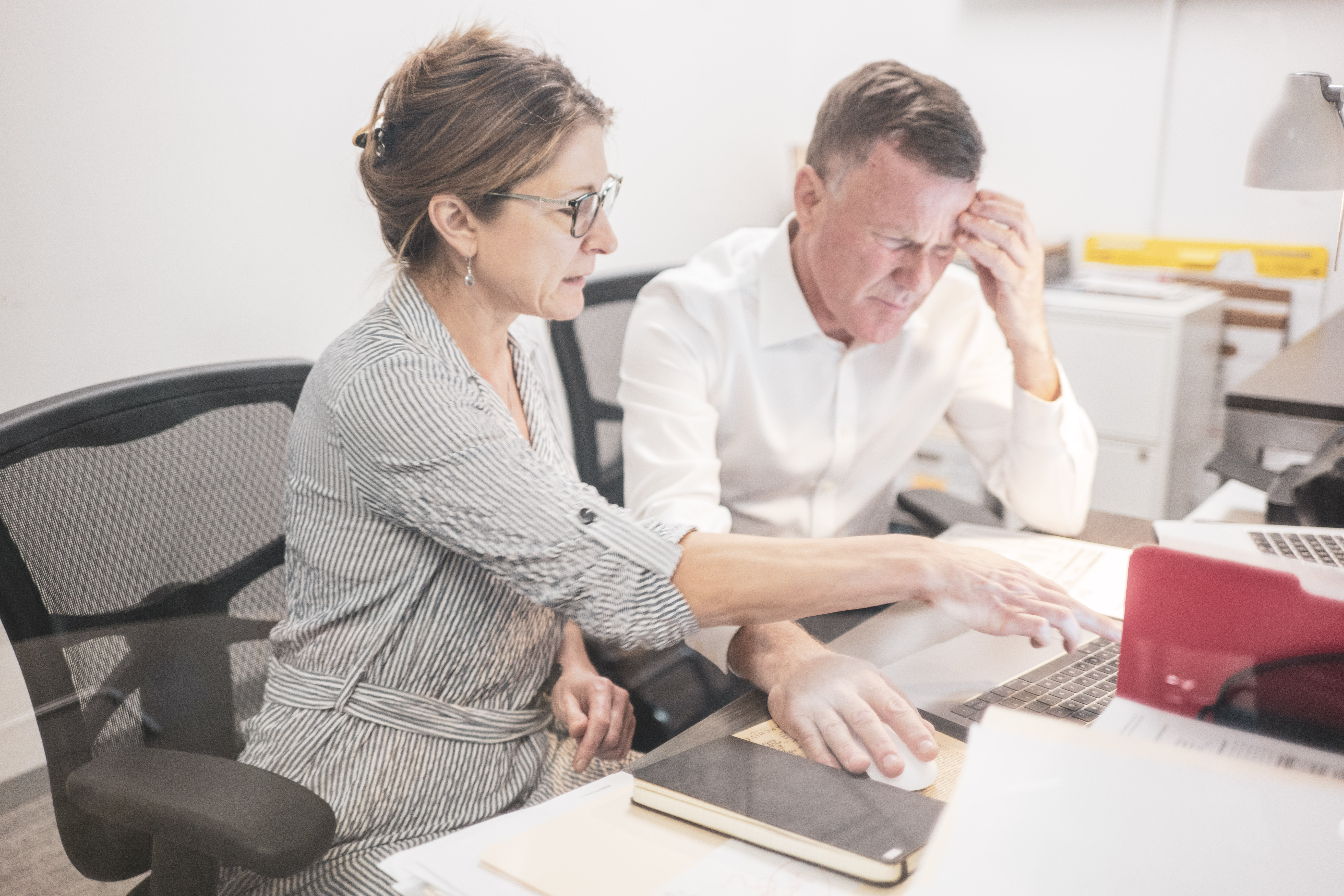 A person and person sitting at a desk with a laptop.
